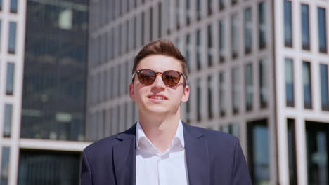 a young successful entrepreneur in sunglasses walks in front of the modern office building