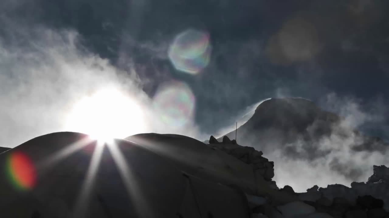 텐트와 구름 뒤에서 떠오르는 태양