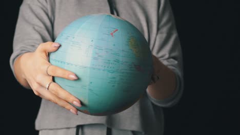 girl's hands twist the geographic globe around its axis