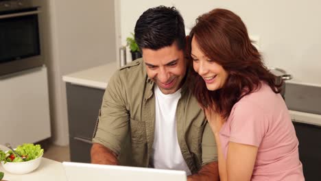 pareja joven charlando y mirando la computadora portátil