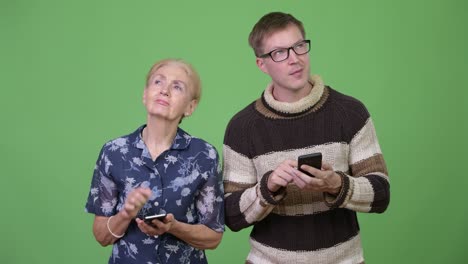 happy grandmother and grandson using phone and thinking together