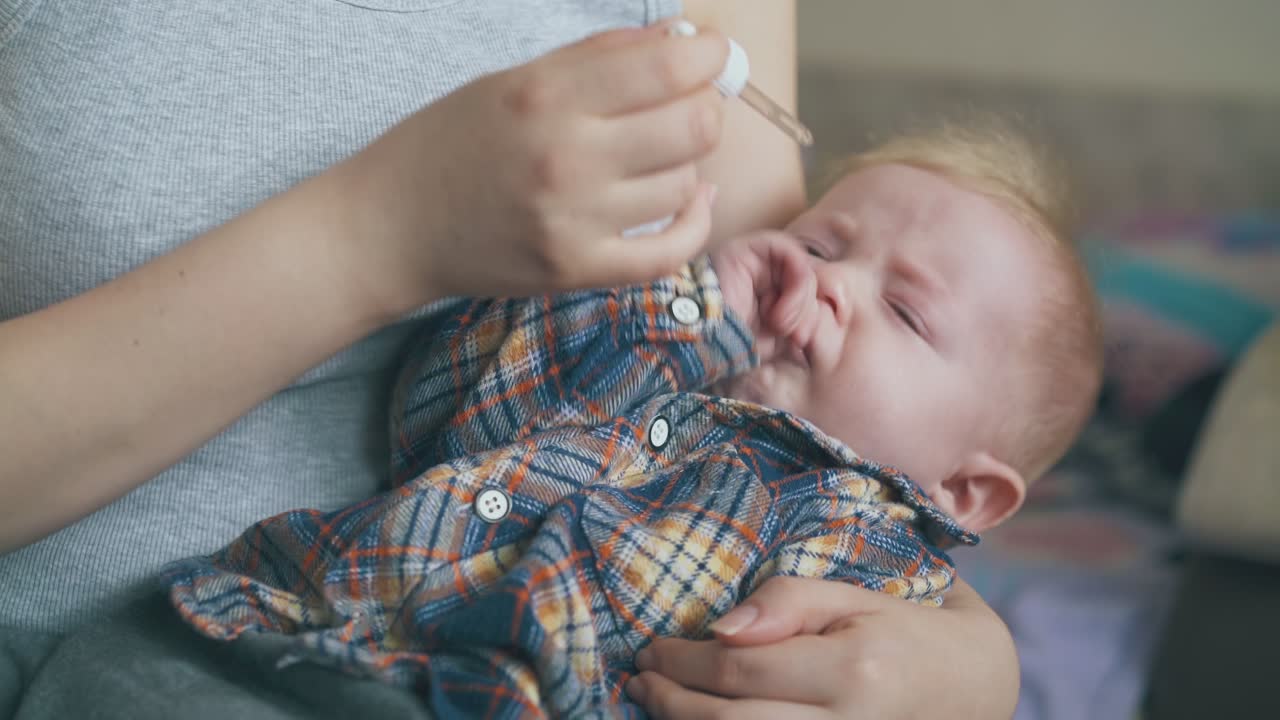 mamá trata de dar gotas nasales a un niño lindo en la habitación