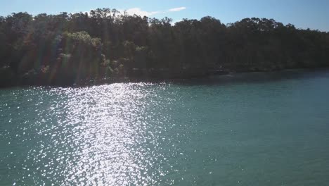 Sunlight-reflections-on-Corindi-River,-Australia.-Aerial-sideways