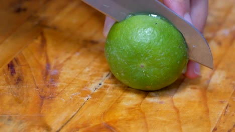 cortando la cal verde por la mitad en la tabla de cortar en la cocina.