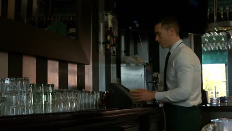 bartender using cash register and tidying up the counter