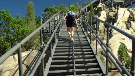 mujer trepando por la escalera de metal construida sobre las rocas en la montaña gwanaksan en seúl, corea del sur - tiro de ángulo bajo