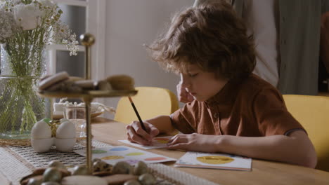 niño dibujando tarjetas de pascua con la familia