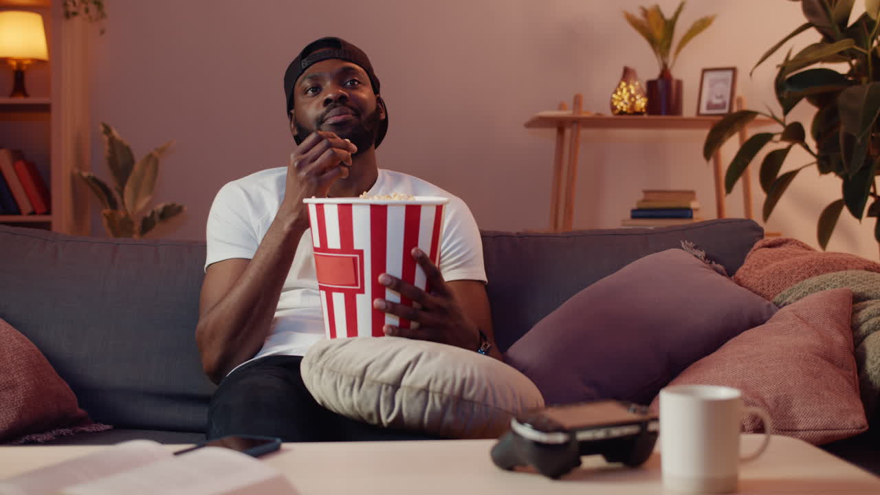 Man watching TV with popcorn on the couch