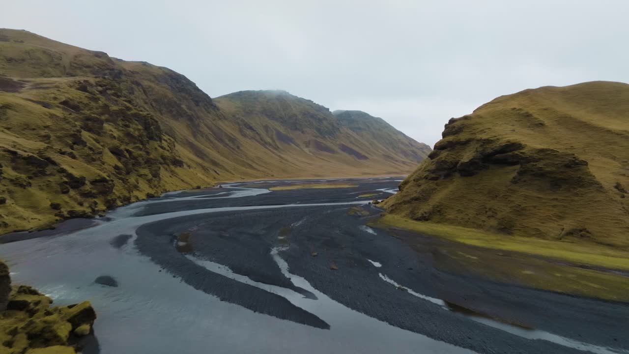 Black sand river flowing in Iceland showing glacier melt erosion - aerial flyover in autumn
