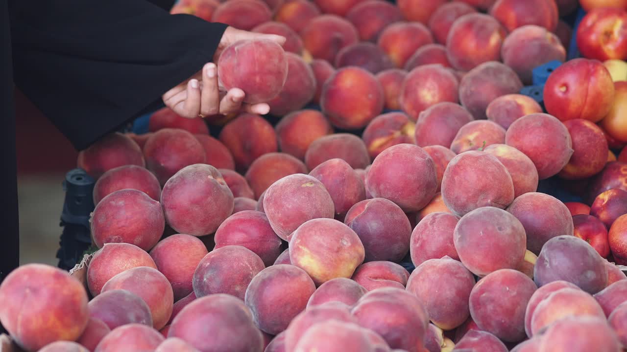 Woman choosing peaches at a market