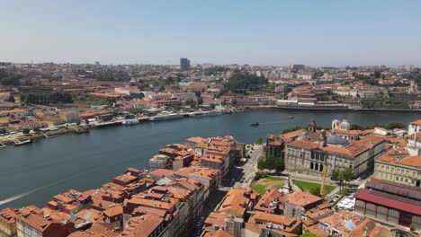 Aerial view of Porto showing historic city center with red-tiled rooftops, Douro River and landmarks including Clerigos Tower and cathedral under bright clear sky in northern Portugal