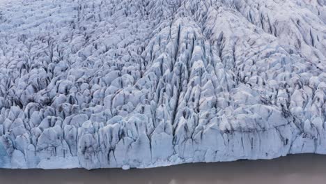 face of fjallsárlón white ice glacier with brown water lagoon, aerial