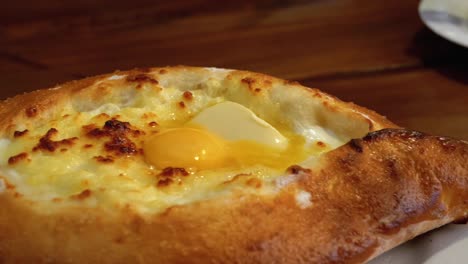 adjarian khachapuri on a table in a georgian restaurant. open bread pie with egg yolk