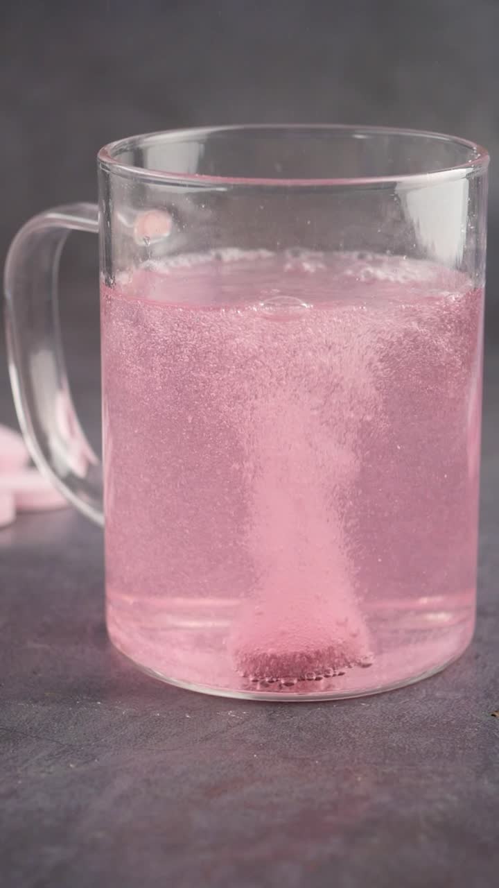 Pastilla efervescente rosa disolviéndose en una taza de cristal