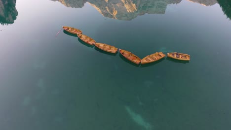 Cinematic-Establishing-Shot-of-Wooden-Row-Boats-with-Mountain-Reflected-in-Water,-Lake-Braies,-Italy