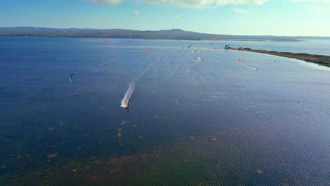 aerial drone backward moving shot of kite surfing from a speed boat at punta trettu, san giovanni suergiu, province of south sardinia in italy on a sunny day