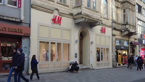 people walking past an h&m store in a city