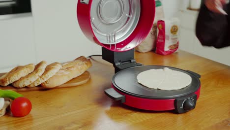 A-stationary-shot-of-putting-pita-bread-inside-the-electric-bread-machine-and-closing-the-lid