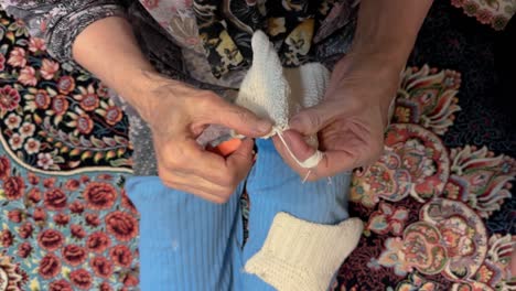 blue pant woman at home old iranian people on carpet peacefully knitting colorful yarn at home village lifestyle cozy domestic craft handmade winter clothing hobby serene traditional textile activity