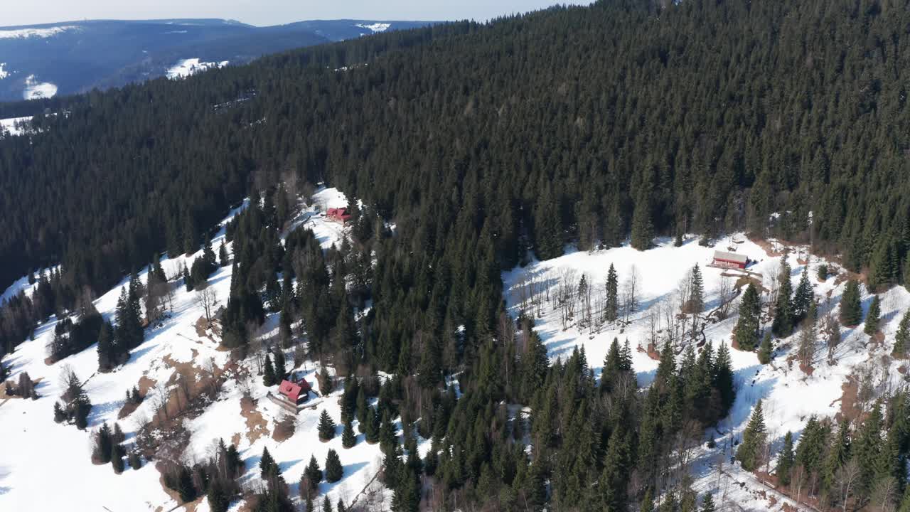 Incredibili montagne e alberi innevati con una piccola baita al centro, ripresa aerea con drone in allontanamento, Natale.