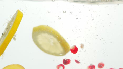 mezcla fresca y sabrosa de frutas caídas en agua con burbujas de aire, aisladas en fondo blanco