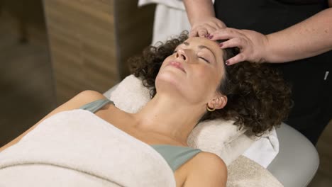 masseuse performing facial massage on woman