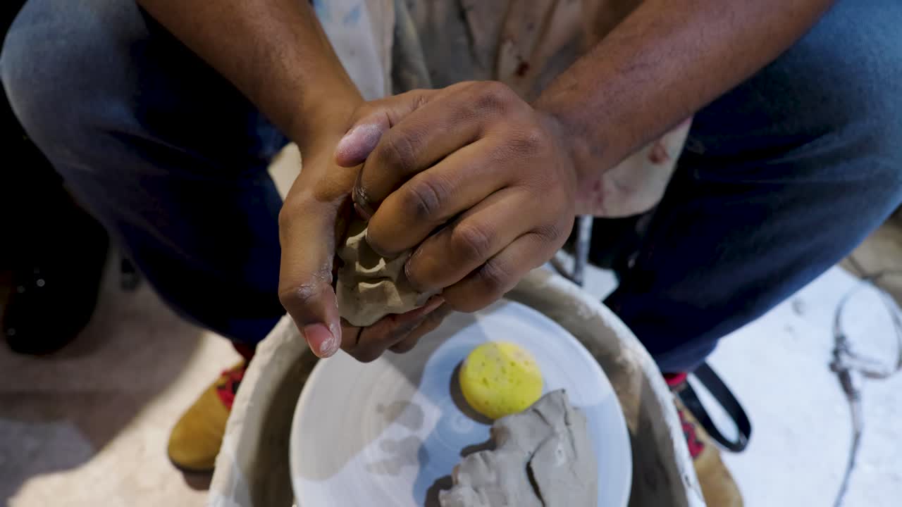 African American black male is excited about molding clay during a pottery class during date night