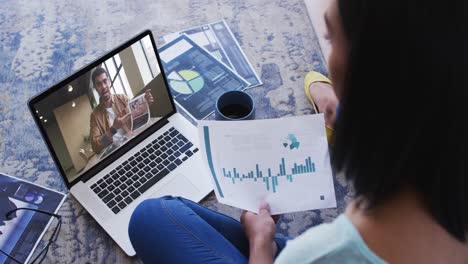 African-american-woman-holding-a-document-having-a-video-call-on-laptop-at-home