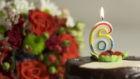 dolly: flower arrangement and birthday cake with burning candle number 6