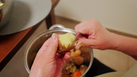close up of elderly hands peeling potato skin slowly in overhead rustic kitchen