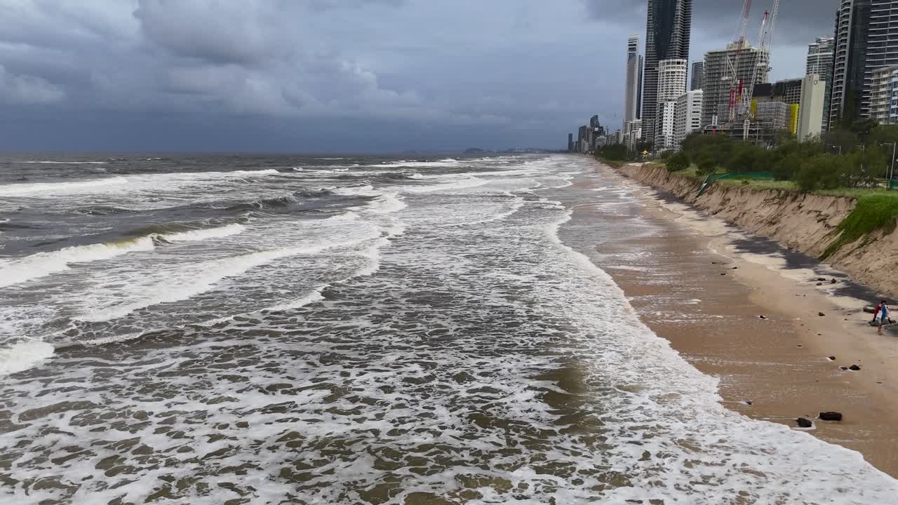 Waves crash against eroded Gold Coast beach under cloudy skies, highlighting storm impact and coastal vulnerability