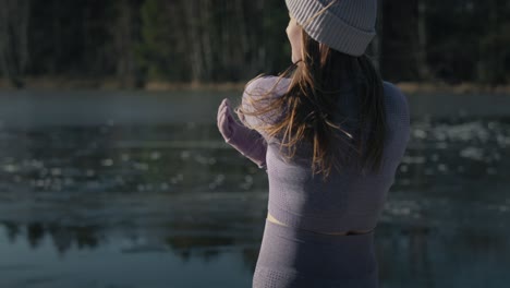 tilt up of young caucasian woman warming up outdoors in the winter.