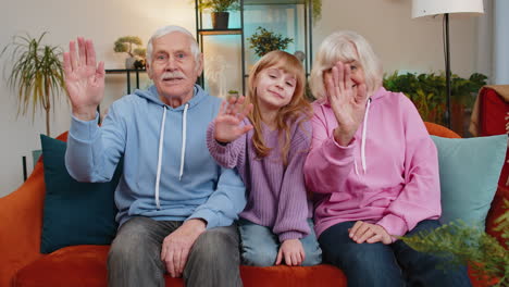 child girl granddaughter with grandparents bloggers waves hand hello hi relaxing making on home sofa