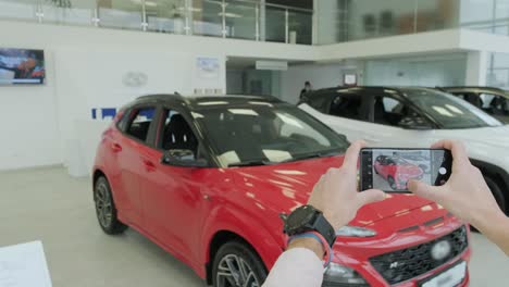 el gerente del concesionario toma fotos de un coche nuevo para la venta. sala de exhibición de coches nuevos de prestigio.