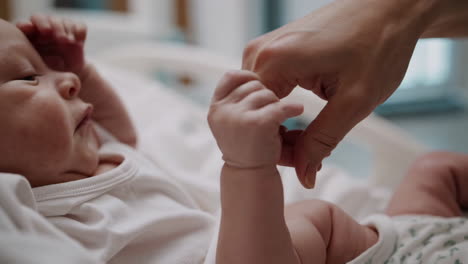 newborn baby holding adult's finger