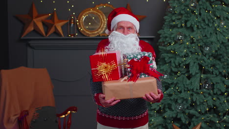 Senior-grandfather-parodies-Santa-Claus-presenting-Christmas-gift-box,-holidays-celebration-at-home