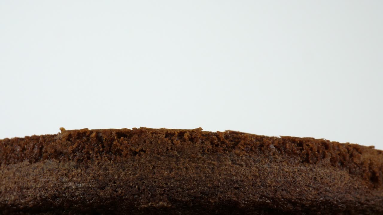 Rotating base of a chocolate cake against a white backdrop
