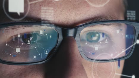 man with glasses works on a global network at computer screen - screen reflected on his glasses - close-up