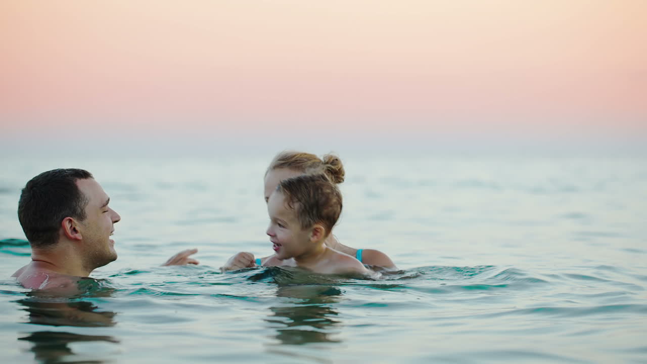 어린 부모 와 아들 이 바다 에서 목욕 하고 있다