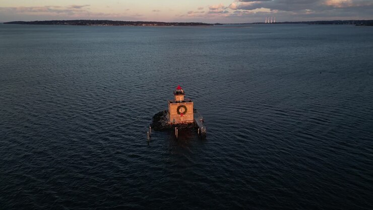 An aerial view of the Huntington Harbor Lighthouse on Long Island, NY at sunset, with a Christmas wreath