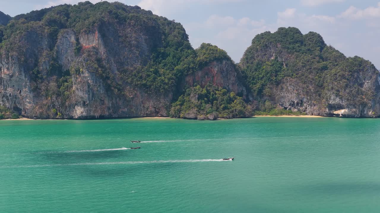 Ampia ripresa aerea di scogliere calcaree tropicali e mare turchese con barche a Krabi, Thailandia