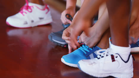 chicas atando cordones de zapatos en la cancha de baloncesto