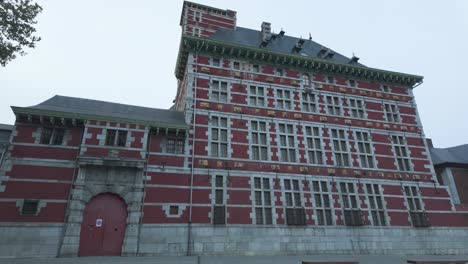 벨기에 리에지에 있는 역사적인 쿠르티우스 박물관의 외관은 은 하늘을 배경으로 장식된 건축적 세부 사항과 활기찬 은 벽돌 전면을 보여줍니다.