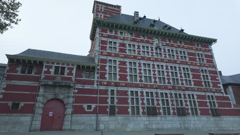 exterior view of the historic curtius museum in liege, belgium, showcasing its ornate architectural details and vibrant red brick facade, set against a muted sky.