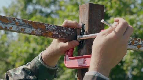 slow motion closeup man fixes metal plank with clamp in yard