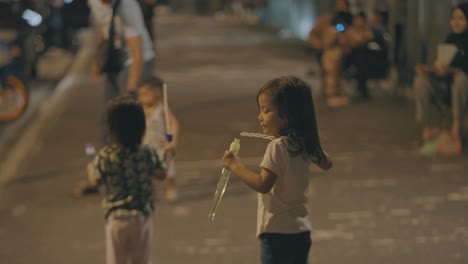 malaysian kids blowing soap bubbles on street of kuala lumpur. blur background.
