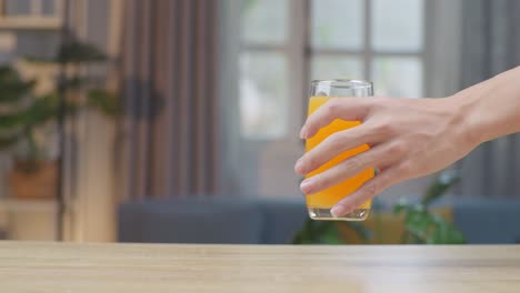 man hand place glass of orange juice on table