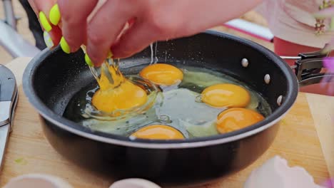 bright yellow egg yolks burst into black pan in slow motion, extreme close up