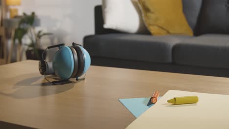 protectores de oídos con lápices de colores y papel en la mesa en casa para el niño diagnosticado con tea