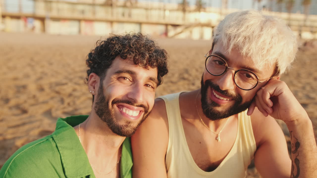 Coppia gay felice che sorride insieme su una spiaggia sabbiosa al tramonto